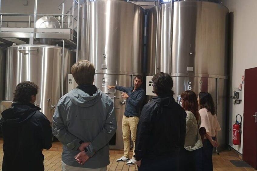 A group of people observing large stainless steel tanks in a facility. 4