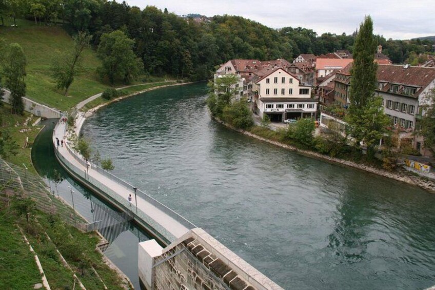 Une rivière avec un pont, des bâtiments et de la verdure. 2