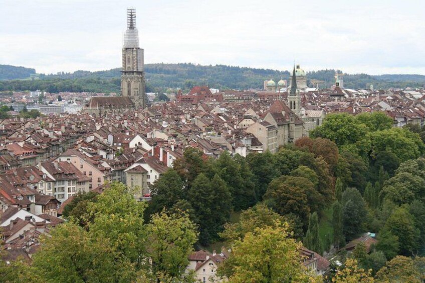 Un paysage urbain caractérisé par une tour imposante, des immeubles d’habitation denses et une végétation luxuriante environnante. 4