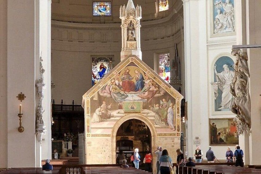 L’intérieur d’une église, avec un autel central, des vitraux et une grande peinture murale. 4