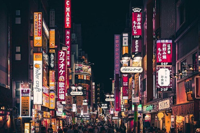 Une rue animée d’une ville, de nuit, avec des enseignes et des bâtiments illuminés. 2