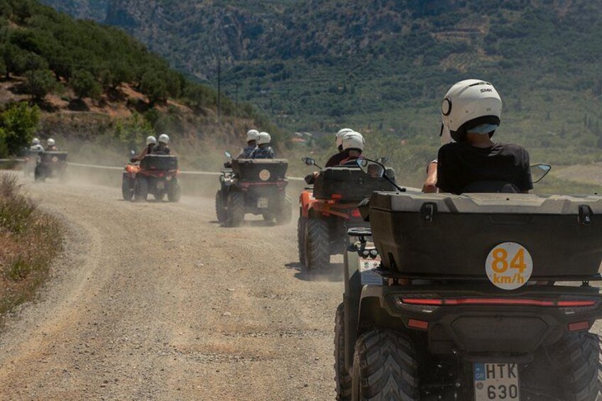 A convoy of off-road vehicles on a dirt road with mountainous terrain in the background. 4