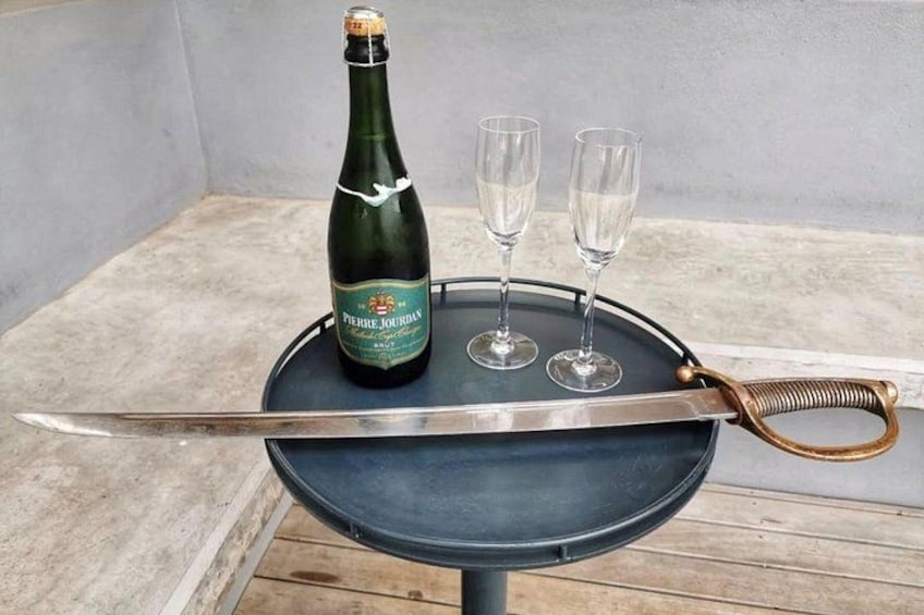 Une bouteille de champagne, deux verres et un grand couteau sur une table. 1