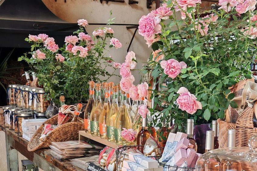 Un étal de marché avec des roses roses, des bouteilles et des paniers. 2