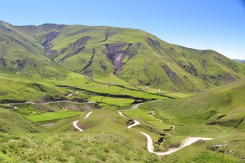 A valley with winding roads, green fields, and hills. 1