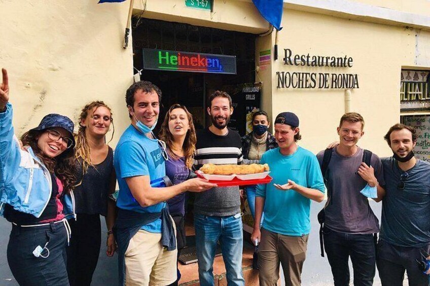 Een groep mensen staat voor een restaurant met een bord waarop 'Heineken' en 'Restaurante Noche de Ronda' staat. 2
