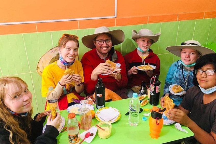 A group of people sitting at a table with food and drinks, wearing cowboy hats. 2