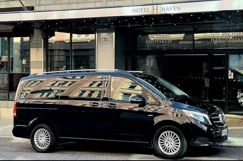 Een zwarte bus geparkeerd voor een hotel met een spiegelende gevel. 5