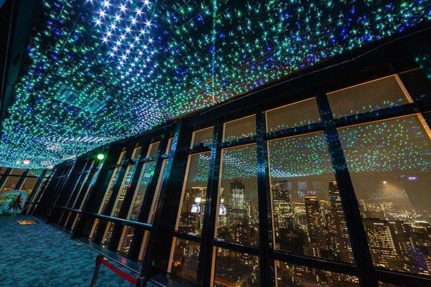 A building with a starry light installation and a cityscape view through large windows. 2