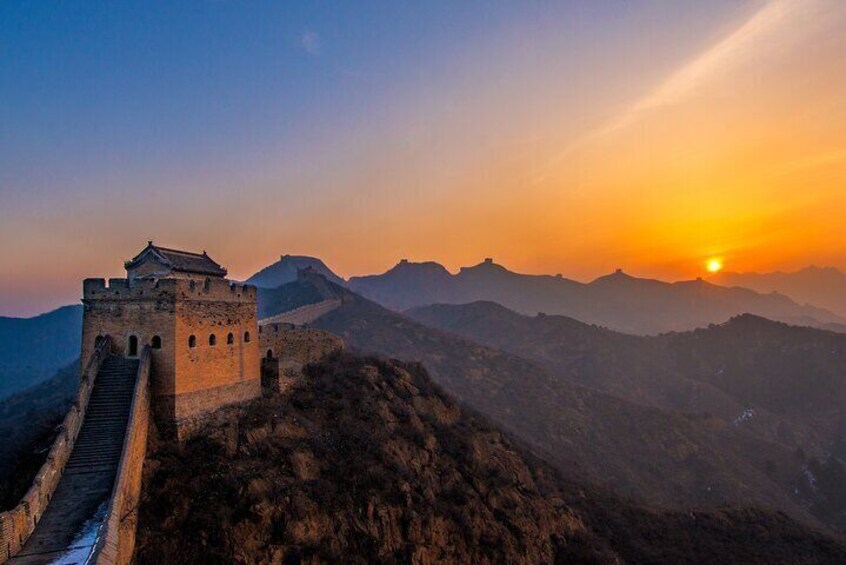 The Great Wall of China at sunset with the sun setting behind the mountains. 3