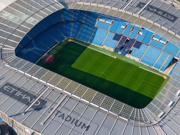 An aerial view of a stadium with blue seating and a green field. 5
