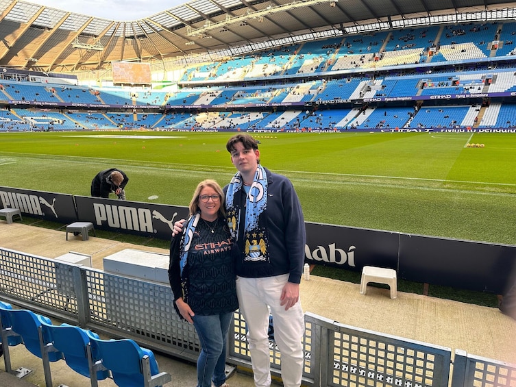 A stadium with blue seating and a green field, a Puma advertisement, and a person wearing a light blue shirt. 2