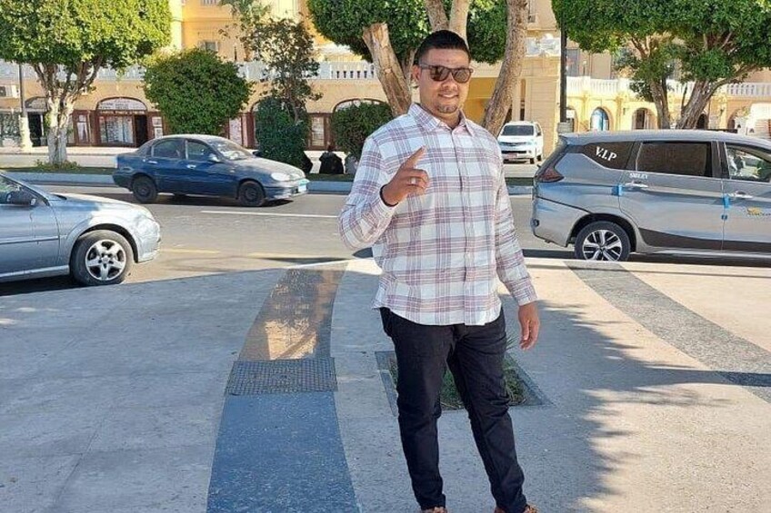 Un uomo in piedi su un marciapiede, con un'auto parcheggiata sullo sfondo. 5