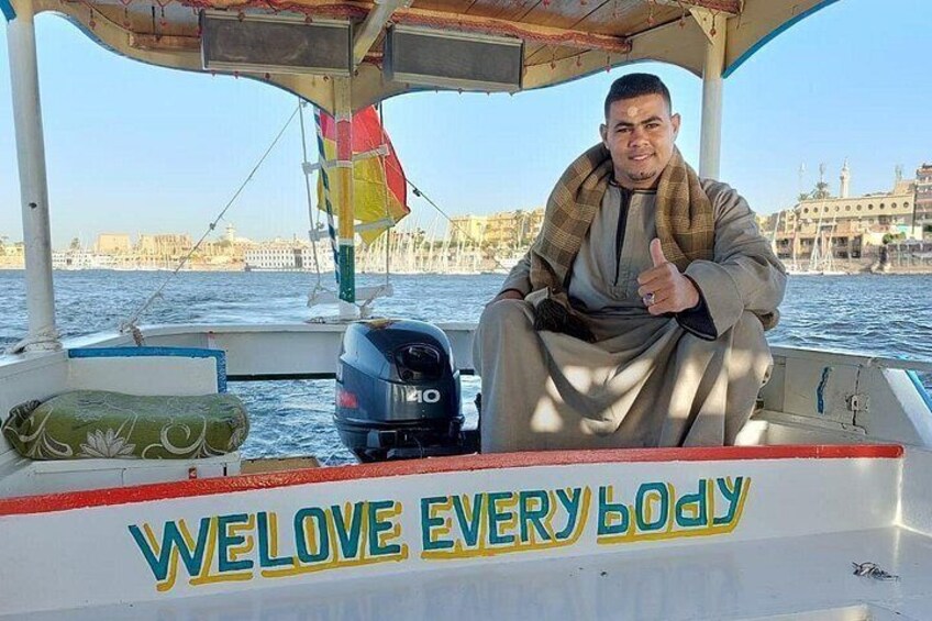 Una barca con una persona che fa il segno dell'ok, uno specchio d'acqua e edifici sullo sfondo. 2