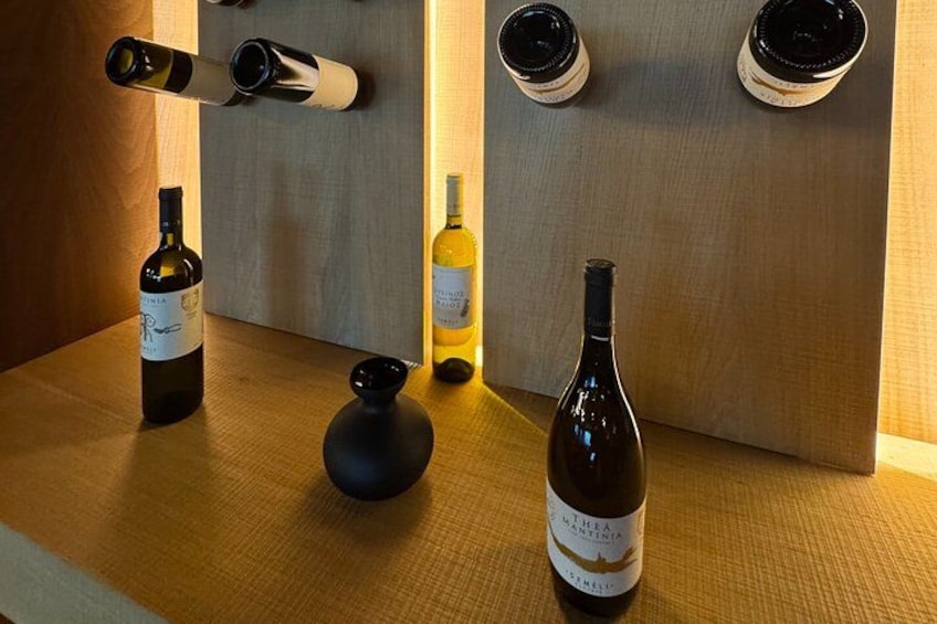 Una estantería para vinos con botellas y una copa de vino sobre una mesa de madera. 2