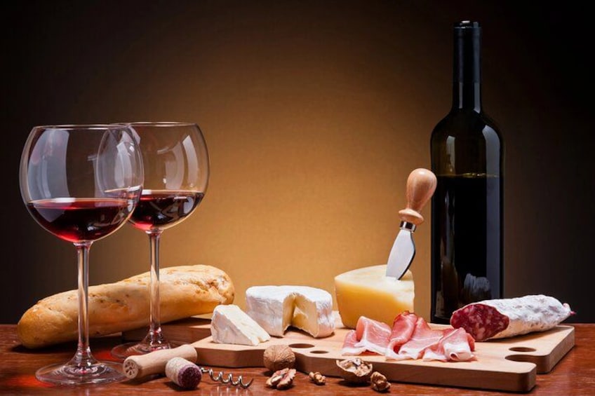 Une planche de fromages avec divers types de fromages, une baguette, une bouteille de vin et des verres à vin. 2