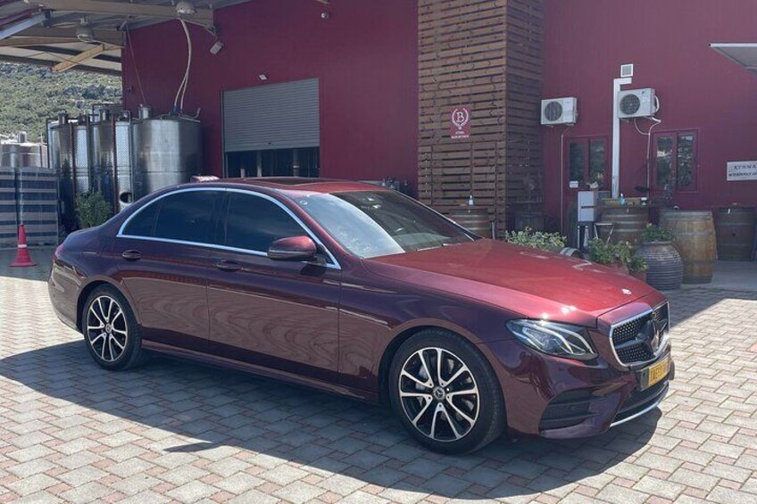 Ein dunkelrotes Mercedes-Benz steht vor einem Gebäude mit roter Fassade. 2