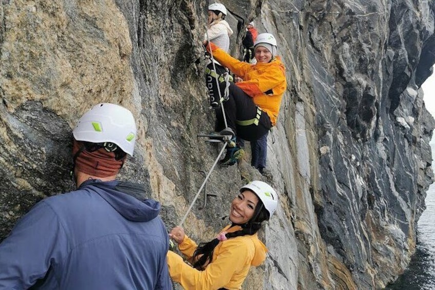 A group of people engaged in a climbing activity on a rocky cliff. 1