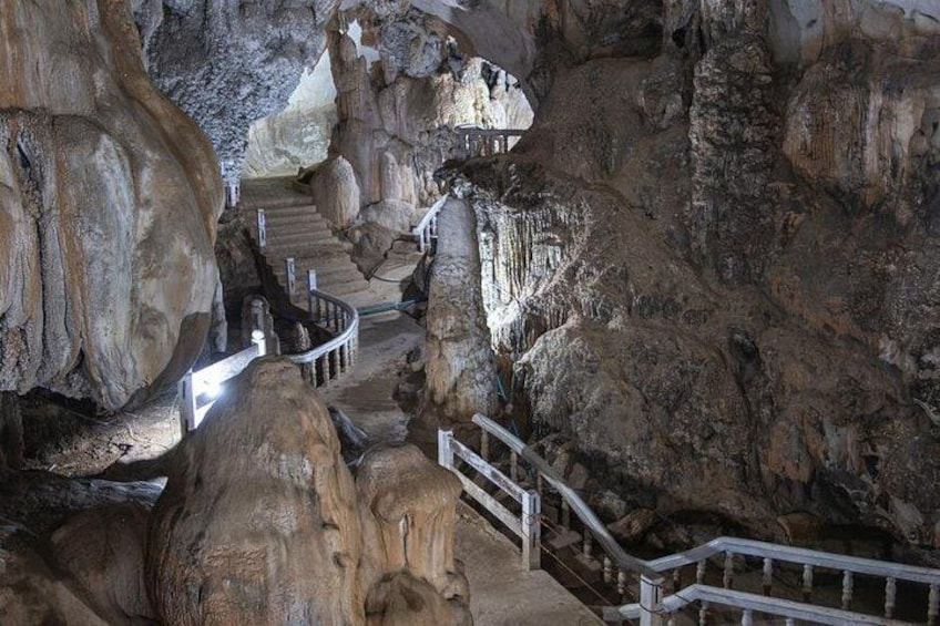 A cave with natural rock formations, a staircase, and railings. 3
