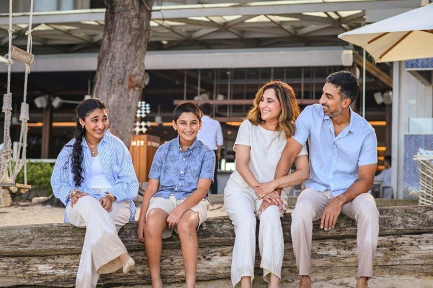 A group of people sitting on a wooden bench outdoors. 2