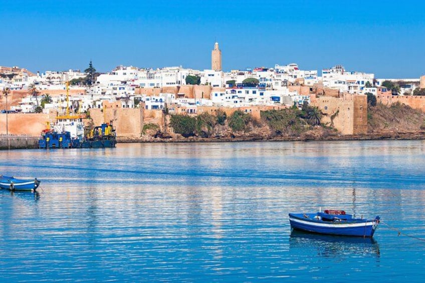 A coastal town with boats on the water, a prominent tower, and white buildings. 2