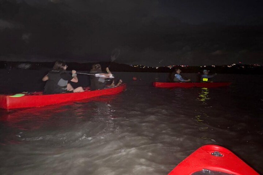 Two people in red canoes on a body of water at night. 5