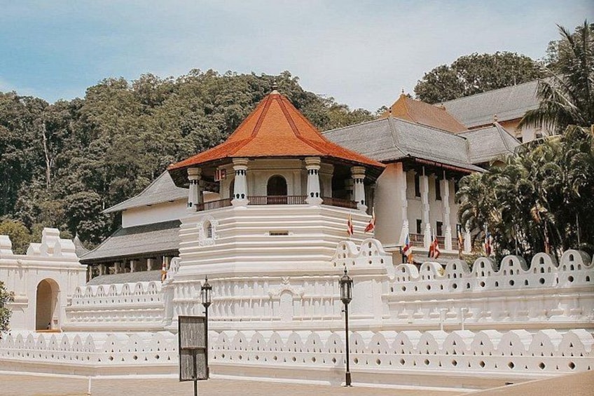 A white temple with a red roof, surrounded by a white fence and palm trees. 1