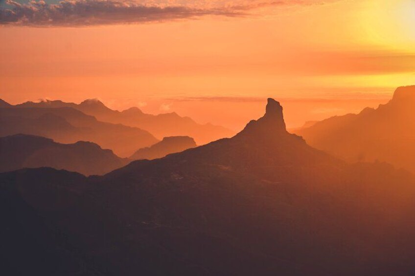 Una catena montuosa al tramonto con una cima particolarmente evidente in primo piano. 2