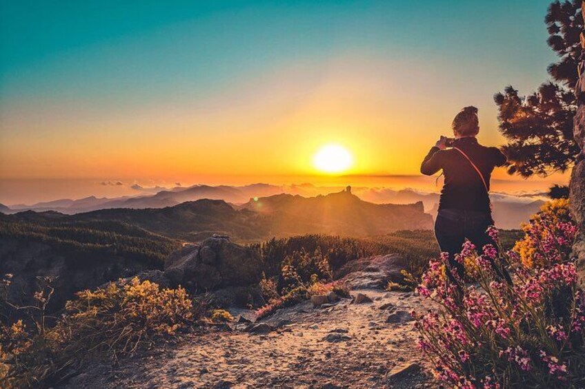 Una persona in piedi su un sentiero montano al tramonto, con vista su una valle e montagne in lontananza. 1