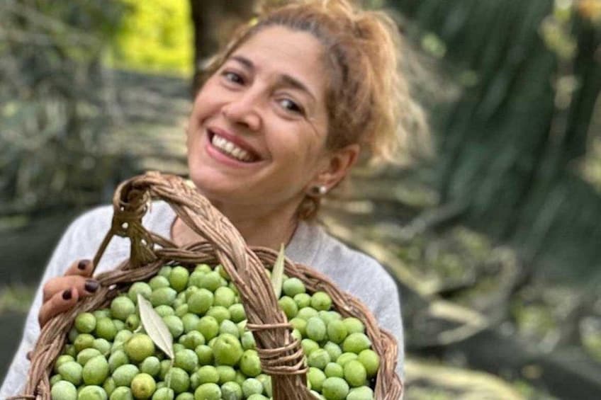 Een persoon die een mand houdt, gevuld met groene vruchten. 1