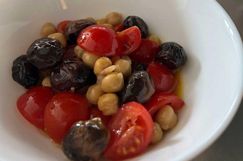 Een schaal met olijven, kikkererwten en cherrytomaten. 3