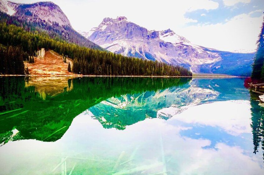 Un lago de montaña con reflejos cristalinos, orilla boscosa y montañas nevadas. 3