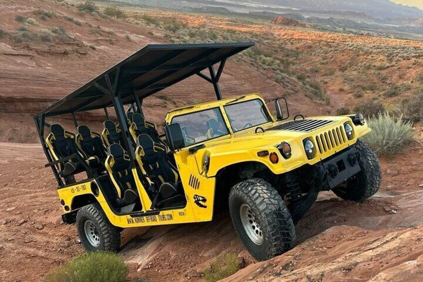 A yellow off-road vehicle with a roof, parked on a rocky terrain. 1