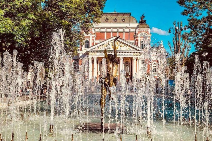 A fountain with water jets in front of a building with classical architecture. 3