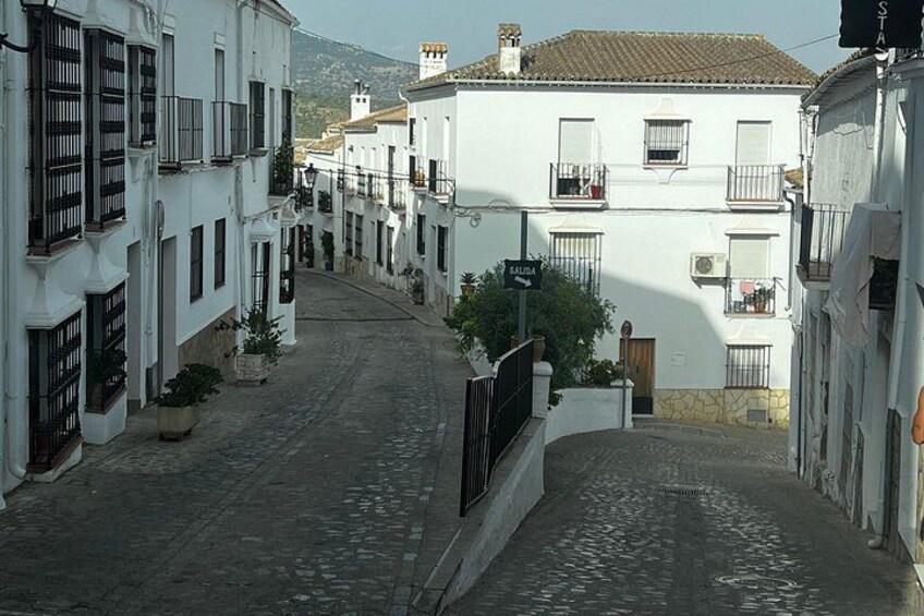 Une ruelle étroite pavée, bordée de bâtiments blancs dotés de balcons et de volets. 2