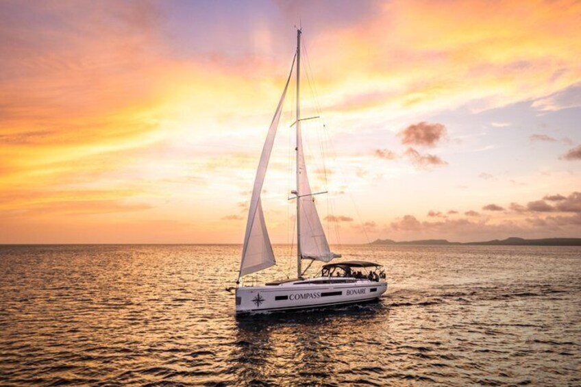 A sailboat named 'Compass' on calm waters during sunset. 1