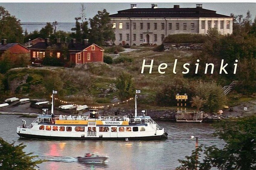 Ein Boot namens SUNNINIS auf einem Fluss in Helsinki, mit Gebäuden und Grünflächen im Hintergrund. 3