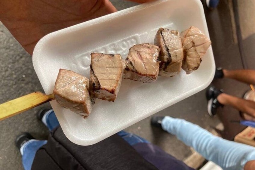 Una persona sostiene una bandeja de plástico con brochetas de carne. 2
