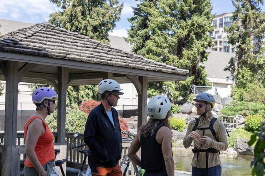 Cuatro personas con casco y equipo de ciclismo de pie bajo un porche. 1