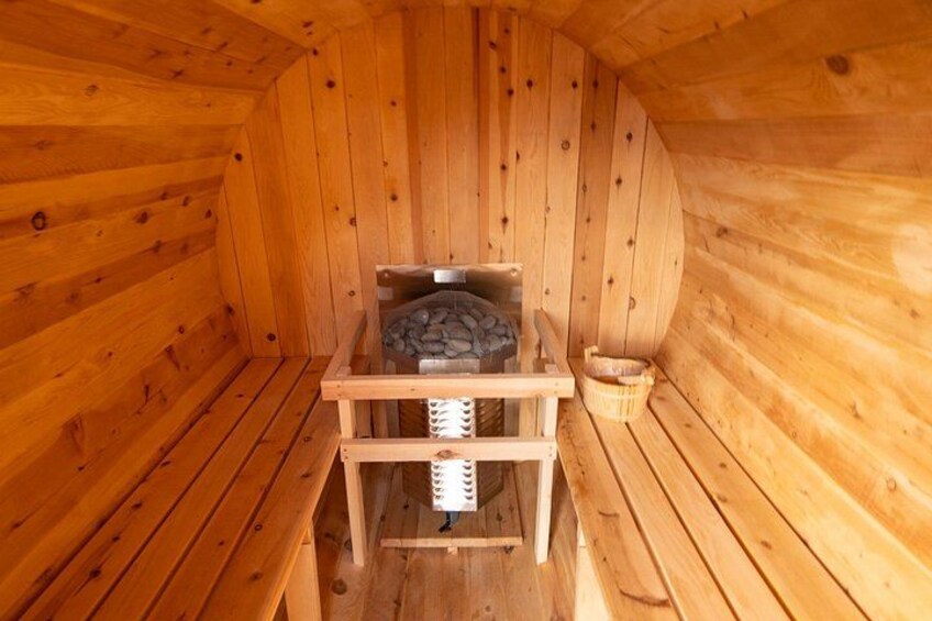 A wooden sauna with benches and a stone heater. 2