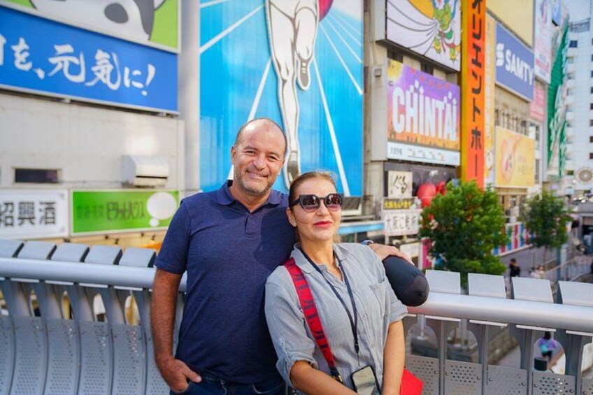 A man and a woman standing on a bridge with a cityscape in the background. 2