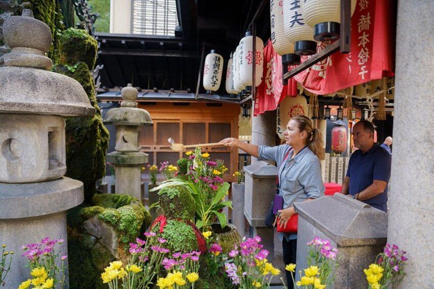 A traditional Japanese shrine with stone lanterns, red banners, and vibrant flowers. 4