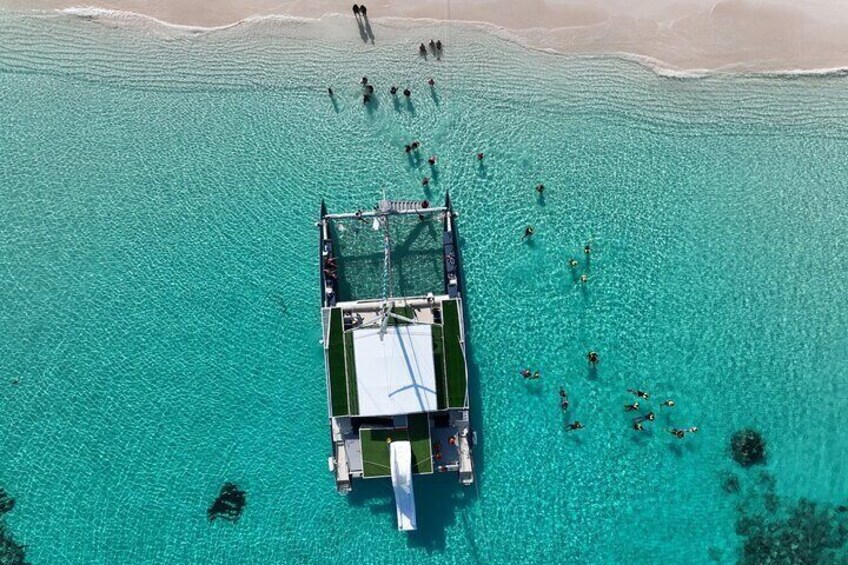 A boat with people swimming in the water around it. 1