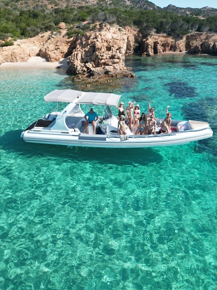 Una barca con persone su un mare turchese cristallino, con scogliere rocciose sullo sfondo. 1