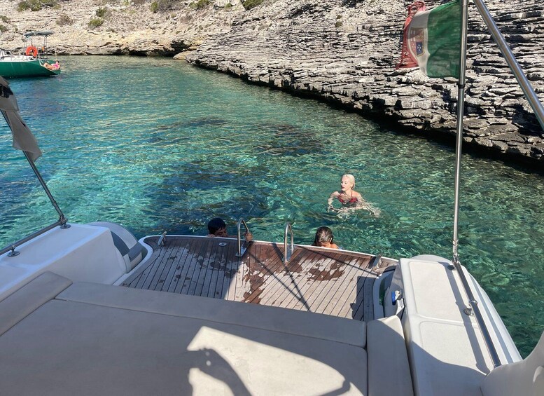 Una barca ormeggiata lungo una costa rocciosa con acqua turchese cristallina. 5