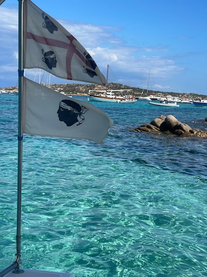 Un palo con delle bandiere, acqua turchese cristallina e barche sullo sfondo. 3