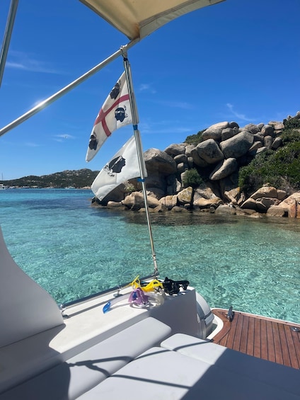Una barca con una bandiera, acqua turchese cristallina e costa rocciosa. 4