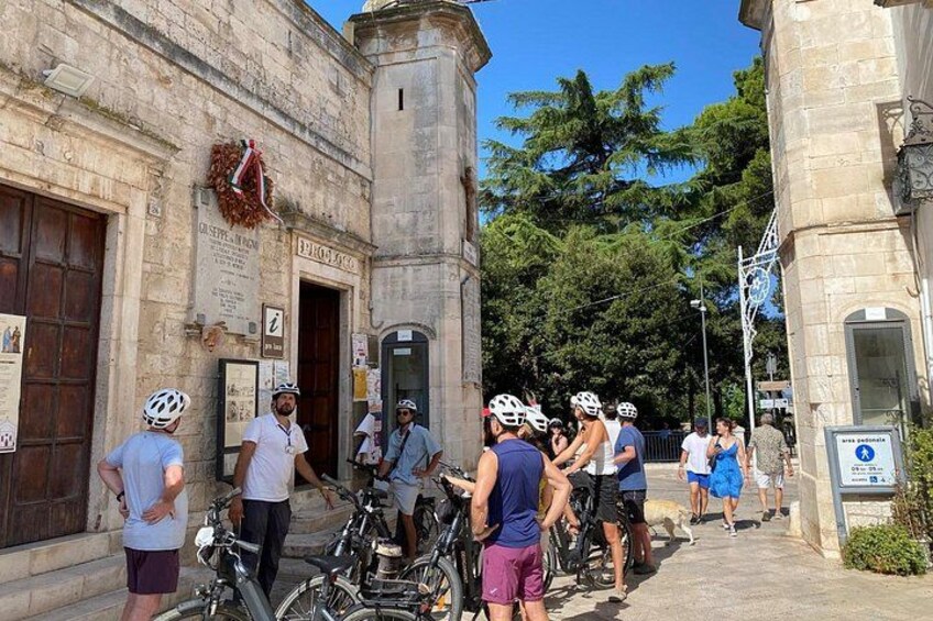 A group of cyclists gathered near a historic building with a clock tower. 2
