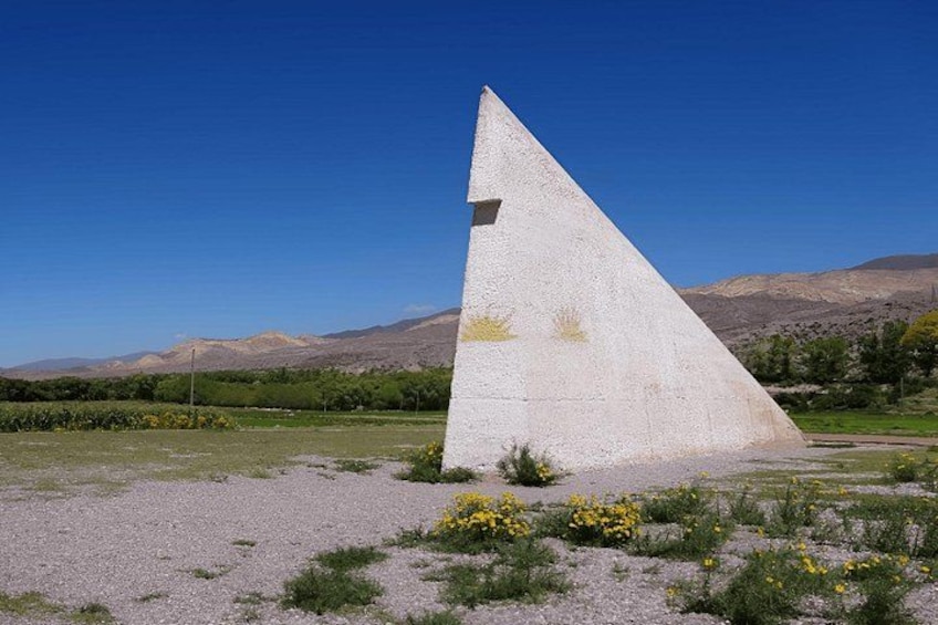 En stor, hvid pyramideagtig struktur i et ørkenlandskab med bjerge i baggrunden. 4