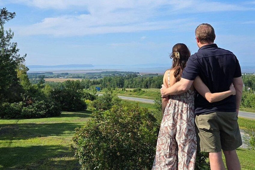 Una pareja se abraza en una colina cubierta de hierba con vistas a una carretera y un paisaje lejano. 4